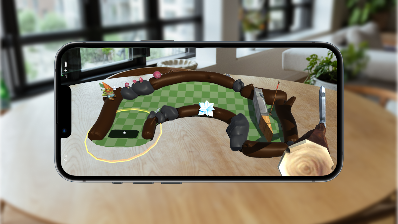 A smartphone shows an augmented reality application in which a putter is attached to the phone and a minigolf course floats in front of the phone. On the left of the course is the ball, around which is a yellow circle. A gnome stands nearby, along with several mushrooms. A sloped curve leads to the right side of the course, where the hole is blocked off by a stone wall and a wooden triangular prism.